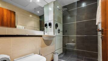 Un baño moderno con cabina de ducha de vidrio, lavamanos blanco y retrete.
