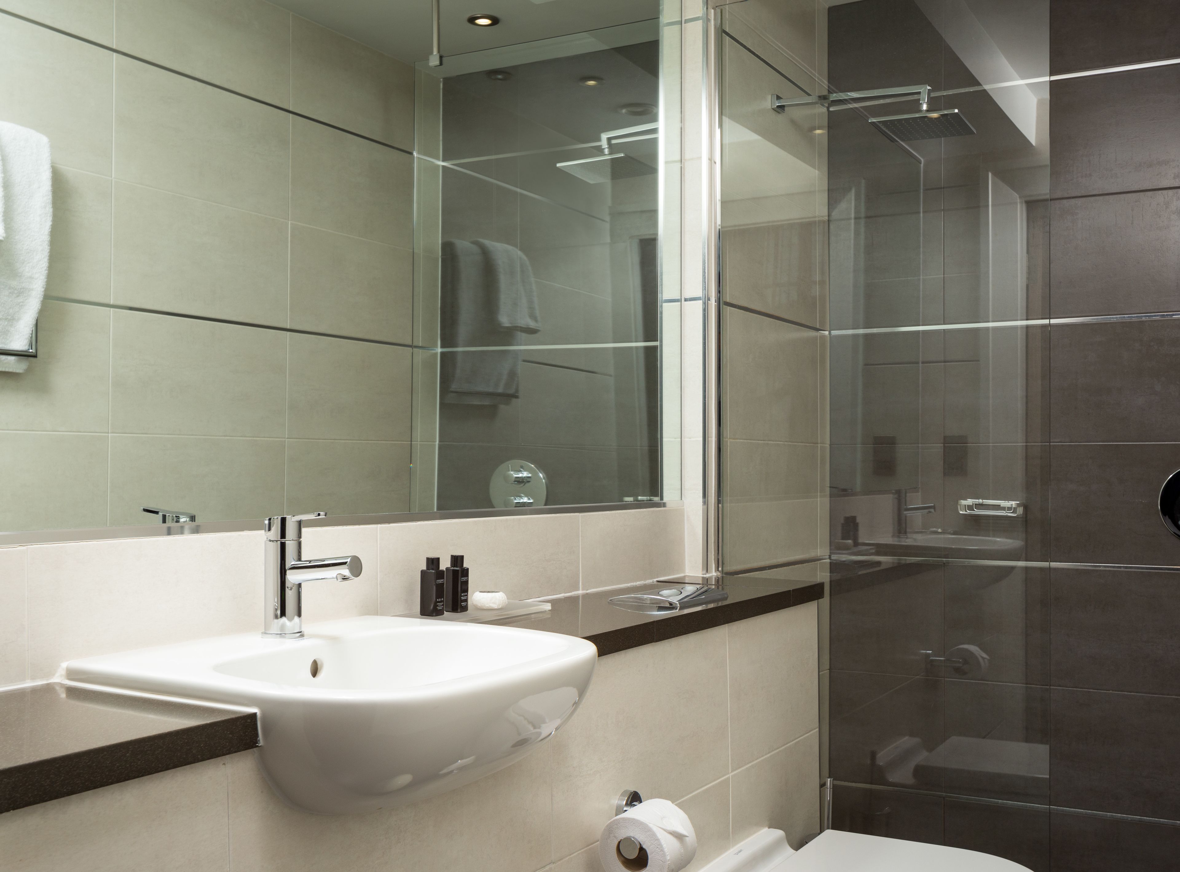 A modern bathroom with a large mirror, a sink, and a shower area.