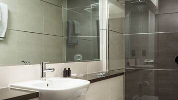 A modern bathroom with a large mirror, a sink, and a shower area.