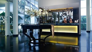 Un espace d’accueil avec une table noire, des fleurs blanches et une cloison en verre.