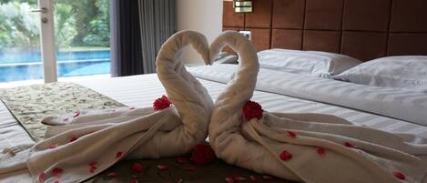Une chambre d’hôtel avec un lit, une décoration en forme de cœur réalisée avec des serviettes et une vue sur la piscine.