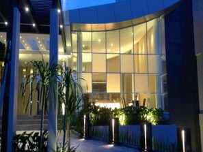 Um edifício moderno com grandes janelas, fachada curva e entrada bem iluminada.