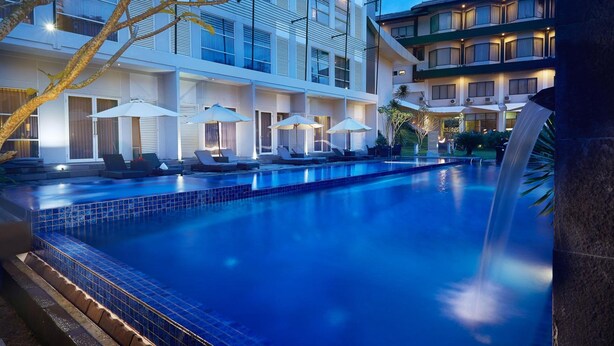 Un hôtel doté d’une piscine, d’un espace extérieur aménagé et d’une cascade décorative.