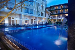 A hotel with a swimming pool, outdoor seating, and a waterfall feature. - Grand Kecubung Hotel (Pangkalan Bun)
