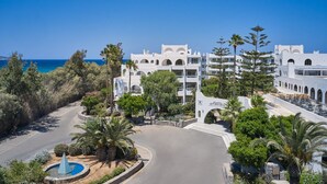 A coastal hotel with white architecture, a curved road, and a view of the sea. - Atlantica Akti Zeus (Malevizi)