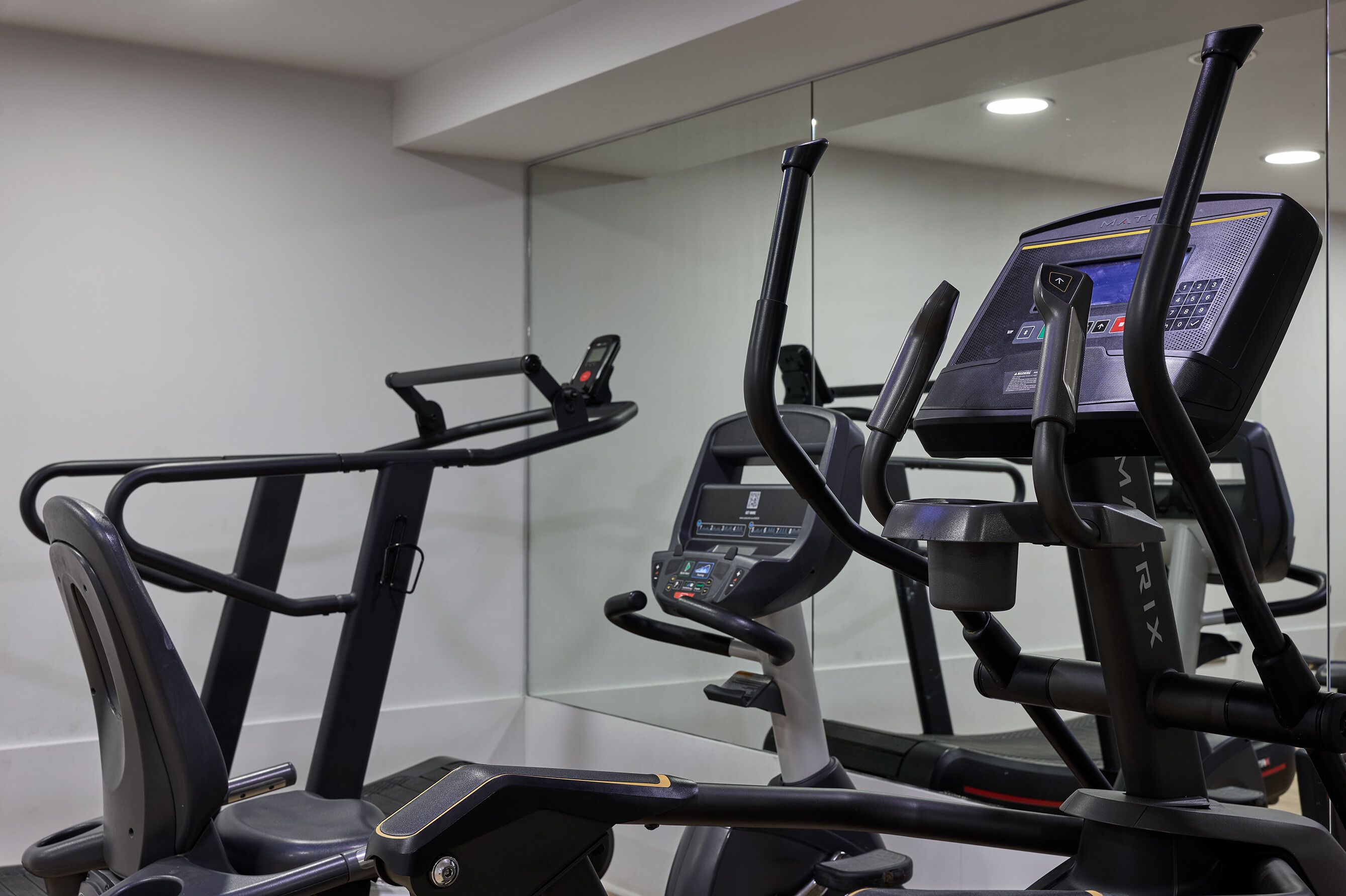 Un gimnasio con equipo de ejercicio, incluyendo cintas de correr y máquinas elípticas.