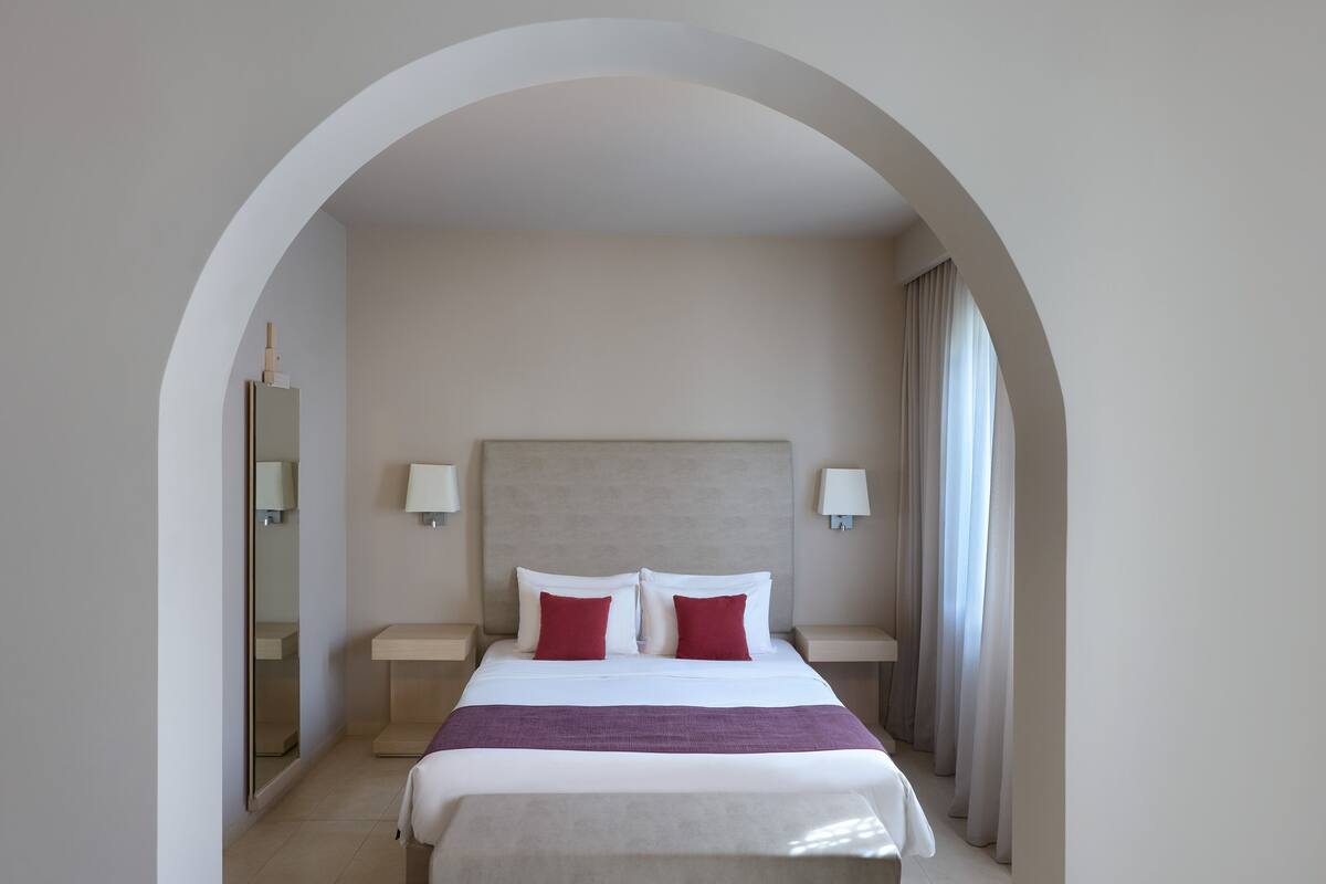A hotel room with a bed, two nightstands, a headboard, and a mirror.