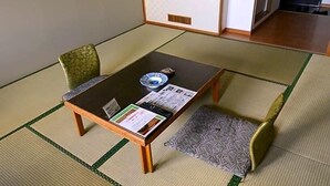 Una habitación con esterillas de tatami, una mesita baja, dos cojines y una pequeña bandeja con un hervidor de tetera.