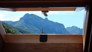 Vista desde el interior de un vehículo, mostrando una cadena montañosa con un pequeño árbol en primer plano.