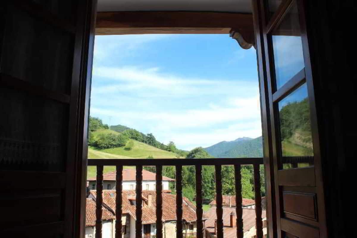 A balcony with a view of a village and hills.