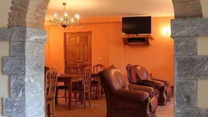 Una sala de estar con un arco de piedra, sofás de cuero, una mesa de comedor y un televisor montado en la pared.