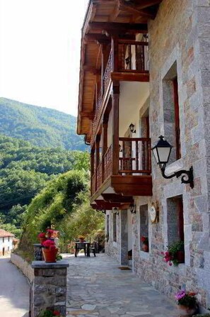 A stone building with wooden balconies and a stone pathway. - Posada Sobrevilla (Camaleno)