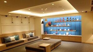 A modern, well-lit room with a sofa, ottoman, and shelves displaying decorative items. - JR East Hotel Mets Hachinohe (Hachinohe)