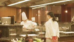 A chef preparing food in a modern kitchen with granite countertops and stainless steel appliances. - JR East Hotel Mets Hachinohe (Hachinohe)