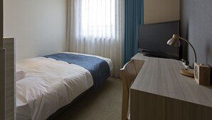 Una habitación de hotel con una cama, un escritorio con televisor y lámpara, y una ventana con cortinas.