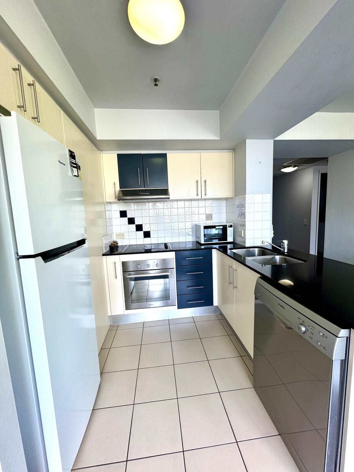 A modern kitchen with white cabinets, a black countertop, a built-in oven, and a dishwasher.