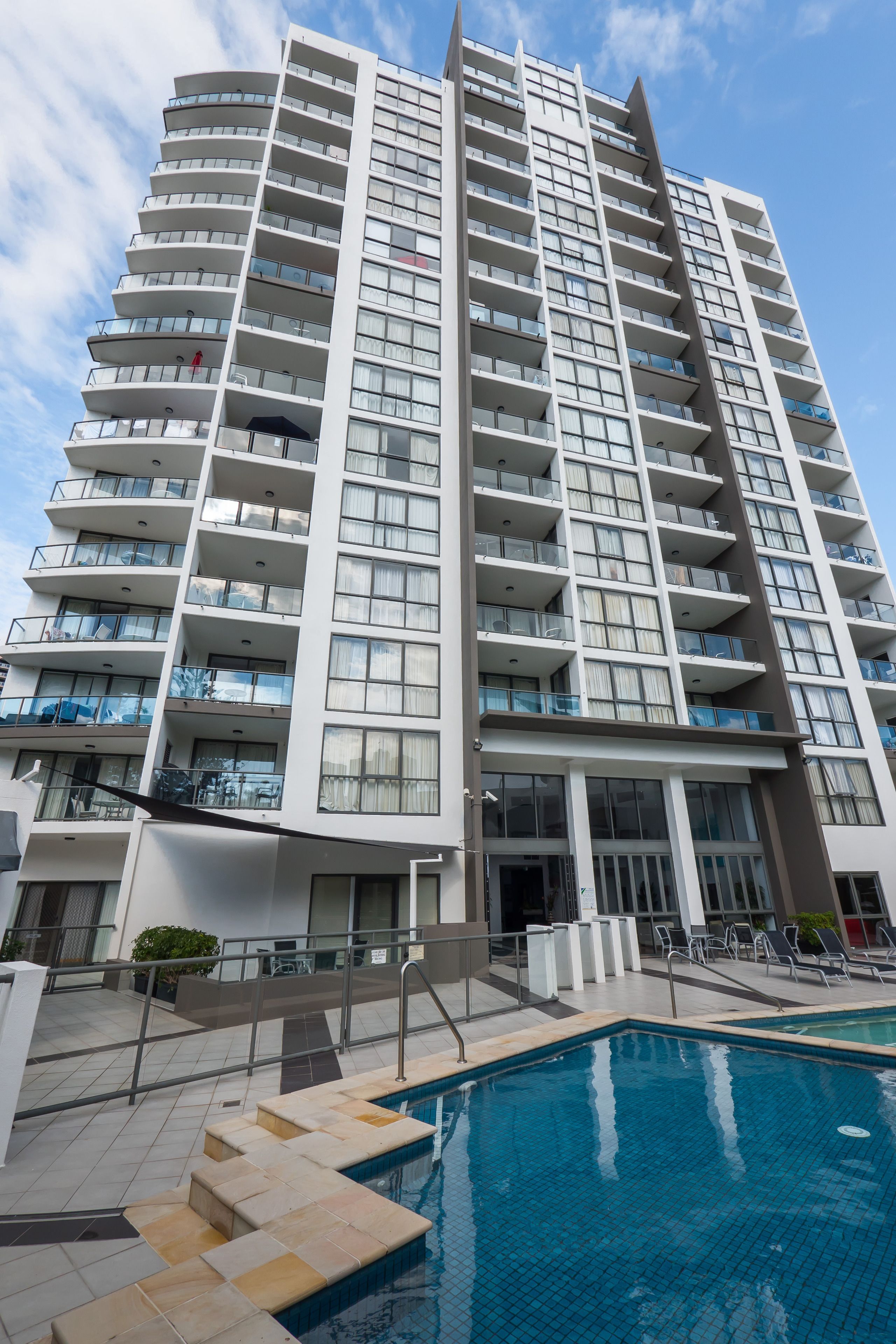 A high-rise hotel with multiple balconies, a swimming pool, and a modern architectural design.