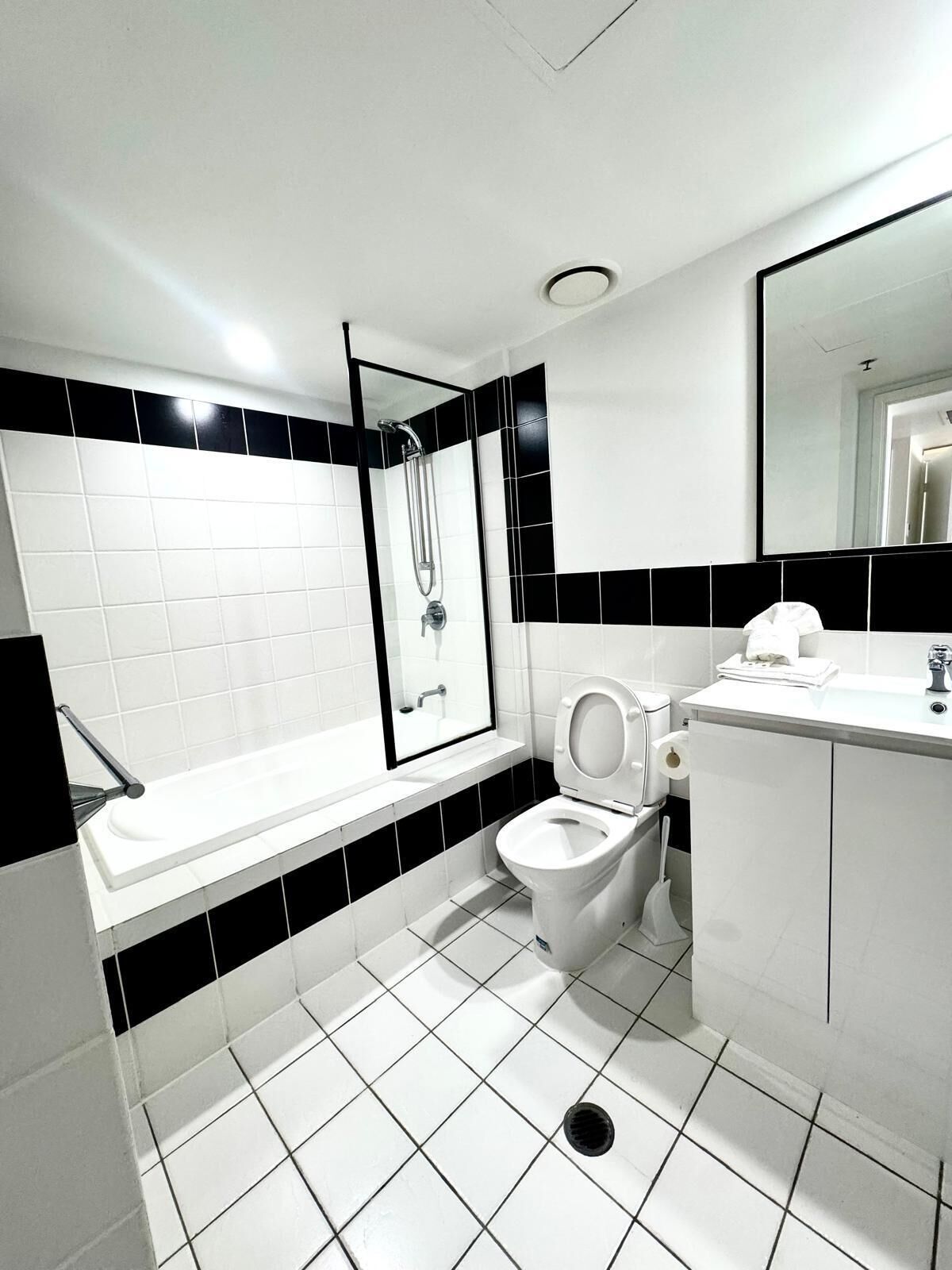 A modern bathroom with a white sink, toilet, and shower.