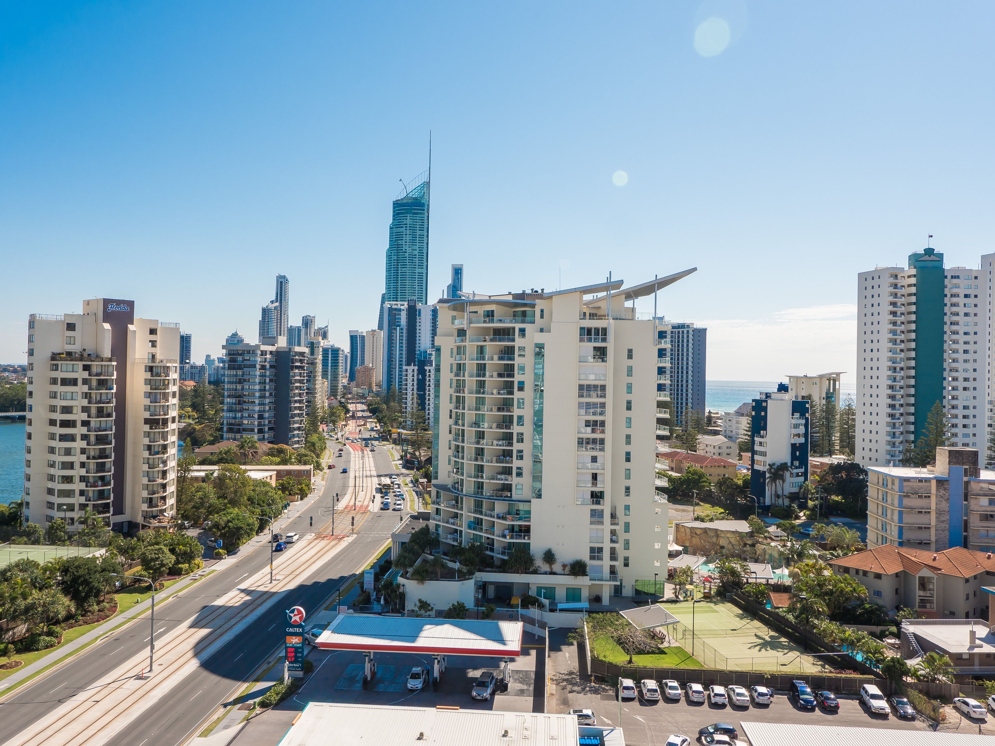 A high-rise hotel with multiple floors, a parking lot, and a view of the city skyline.