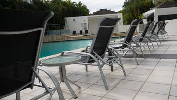 Una piscina al aire libre, sillones reclinables de piscina