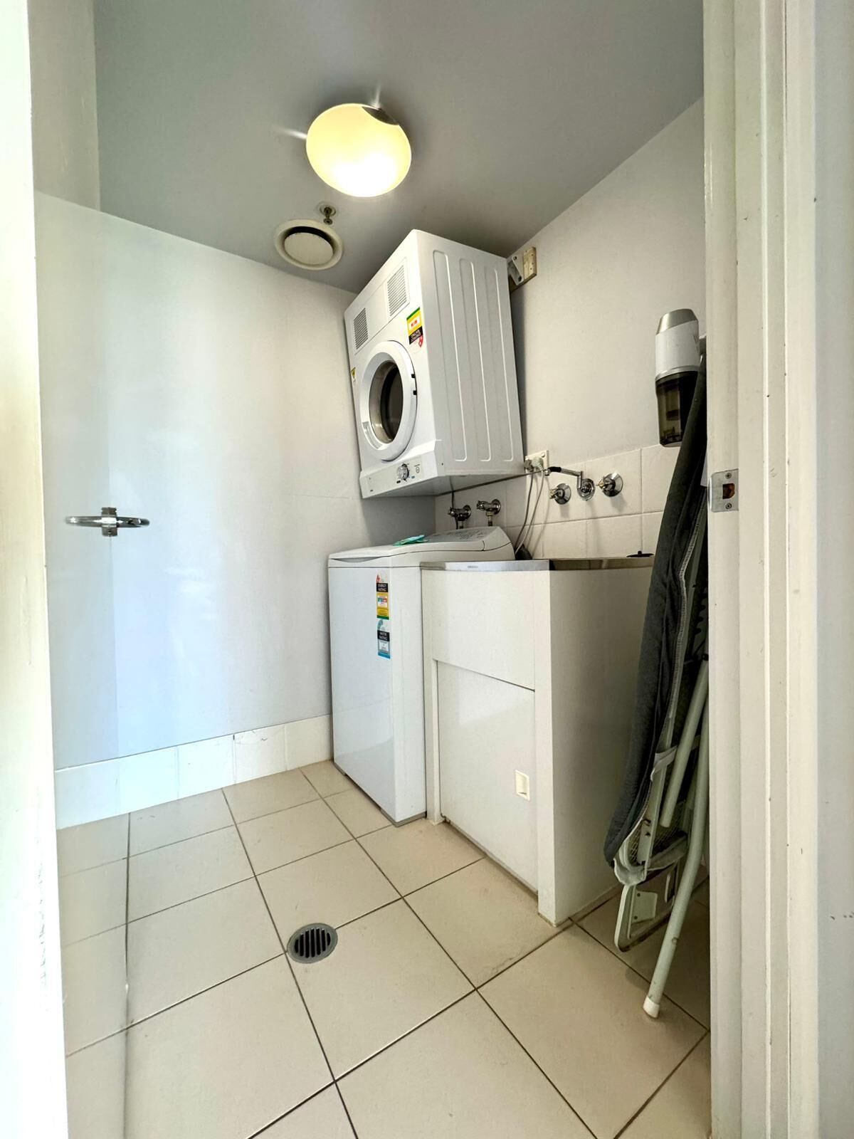 A compact laundry room with a washing machine, dryer, and ironing station.