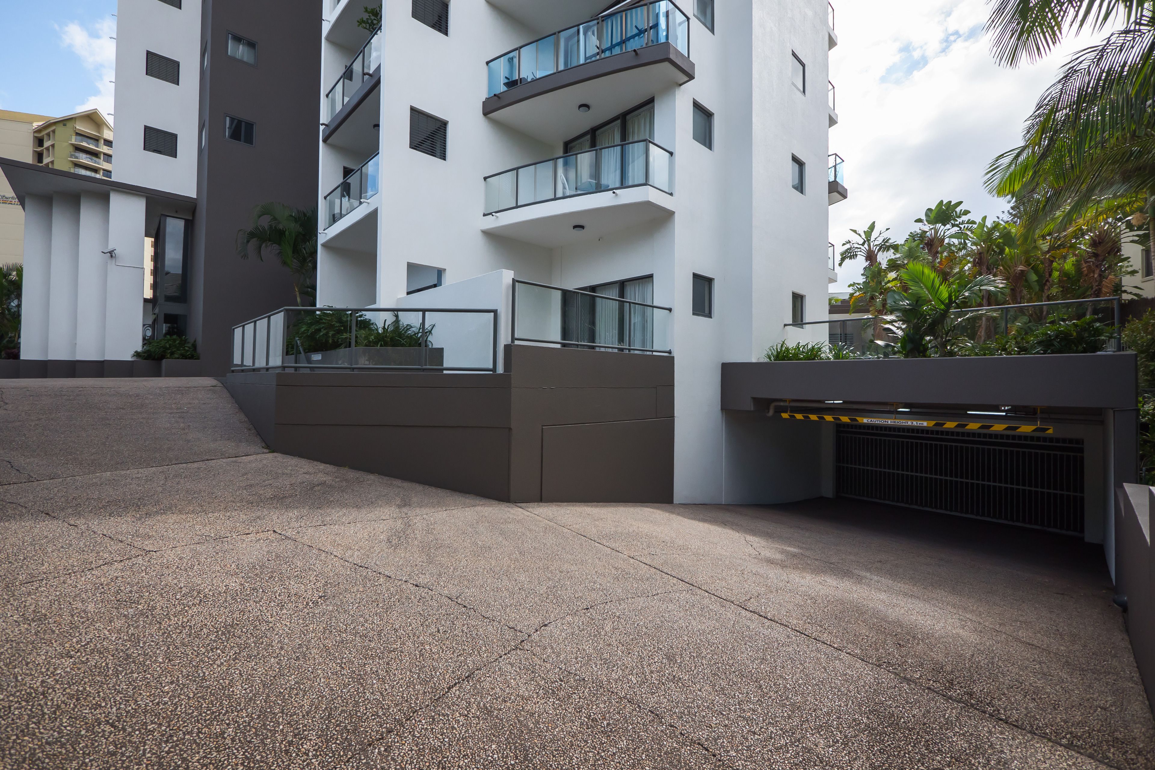 Un bâtiment moderne doté de nombreux balcons, d’une entrée sécurisée par un portail et d’une zone dallée.