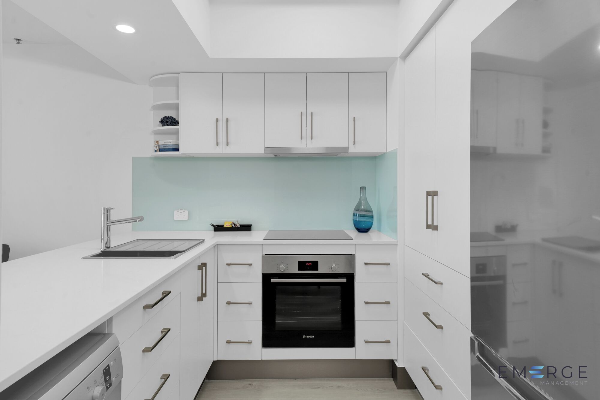 Una cocina moderna con armarios blancos, horno Bosch y lavavajillas integrado.
