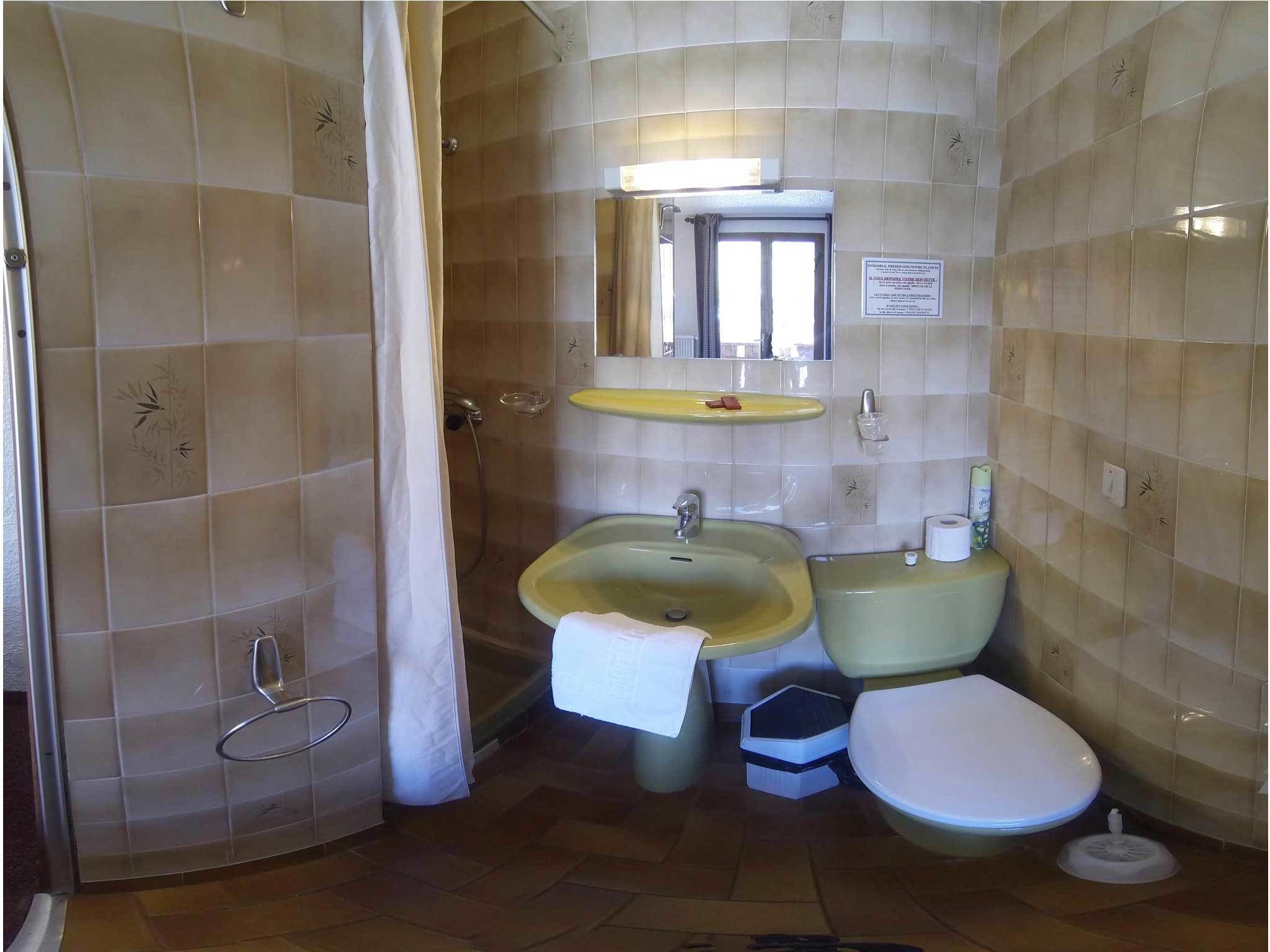 Een badkamer met een douche, twee wastafels, een toilet en een spiegel.