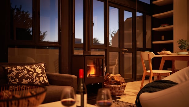 A cozy living room with a fireplace, a sofa, a dining table, and a bookshelf. - Eikehoff Apartment  (Stellenbosch)