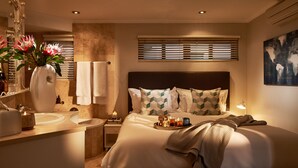 A modern bedroom with a large bed, bedside tables, a vanity with a mirror, and a wall-mounted globe. - Eikehoff Apartment  (Stellenbosch)