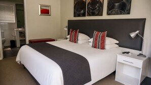 Quarto de hotel com uma cama grande, mesas de cabeceira, escrivaninha e uma cadeira.