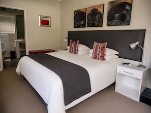 Een hotelkamer met een groot bed, nachtkastjes, een bureau en een stoel.