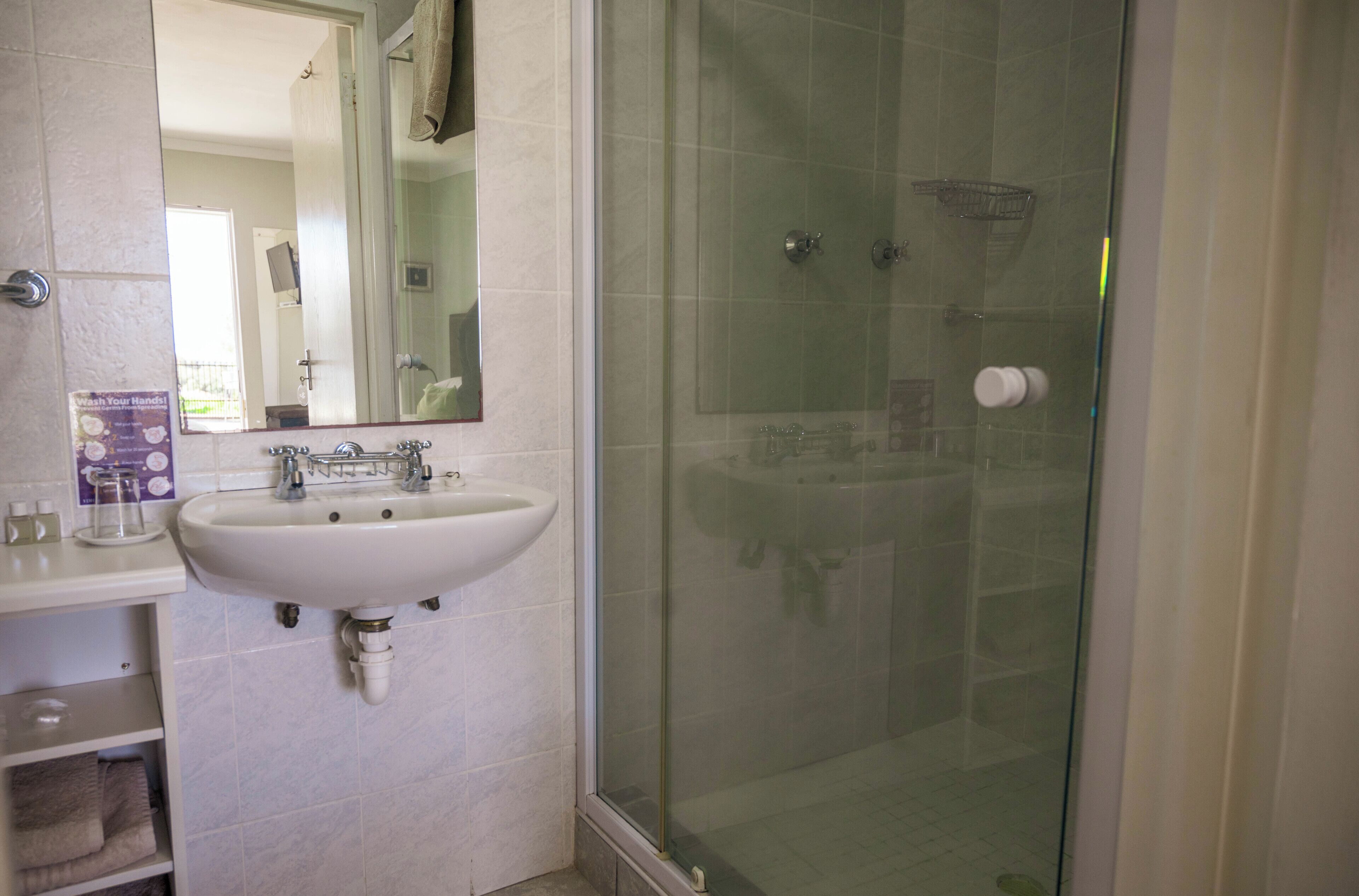 A bathroom with a white sink, a glass shower enclosure, and a mirror.