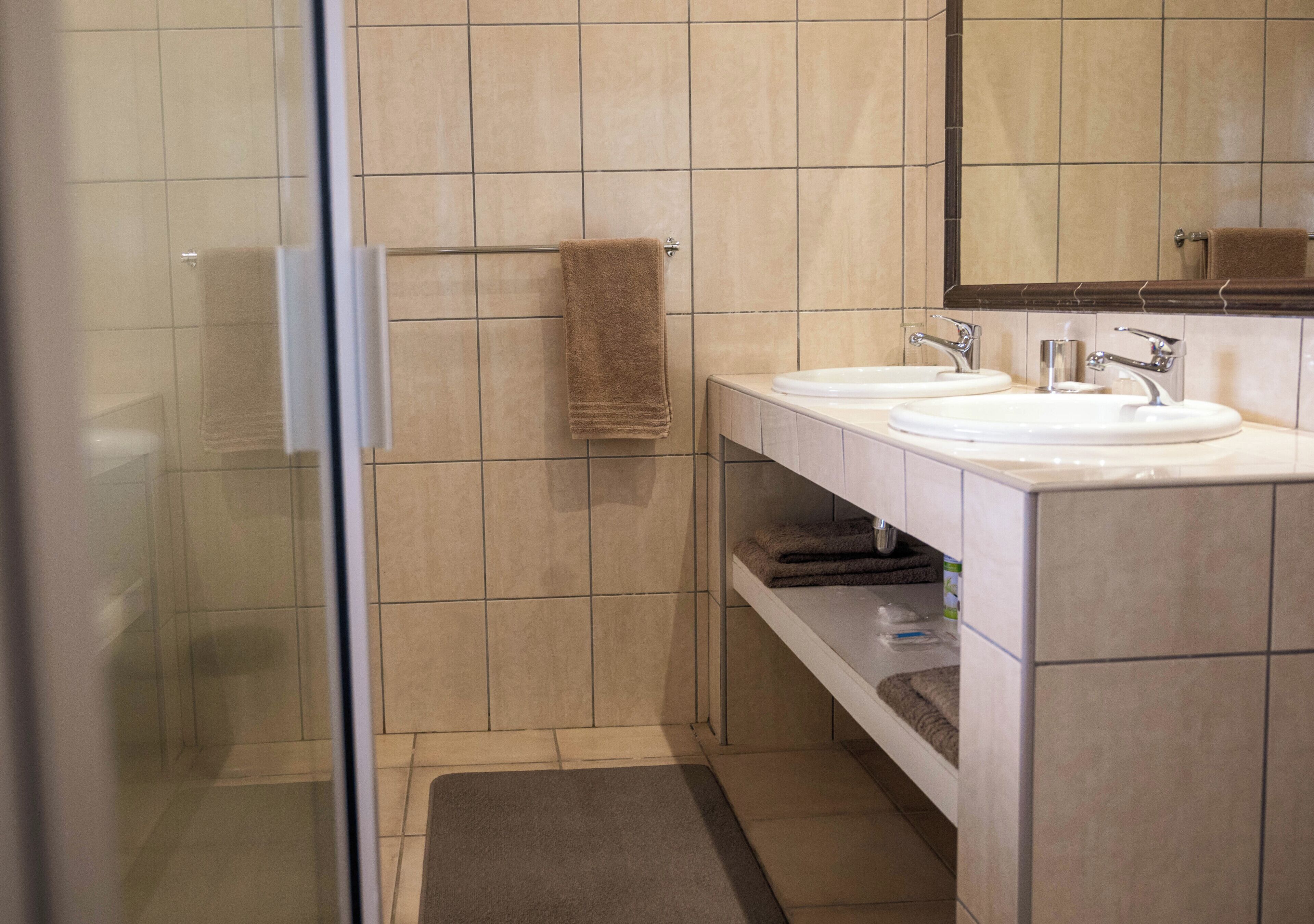A bathroom with a glass shower enclosure, two sinks, and a mirror above the vanity.