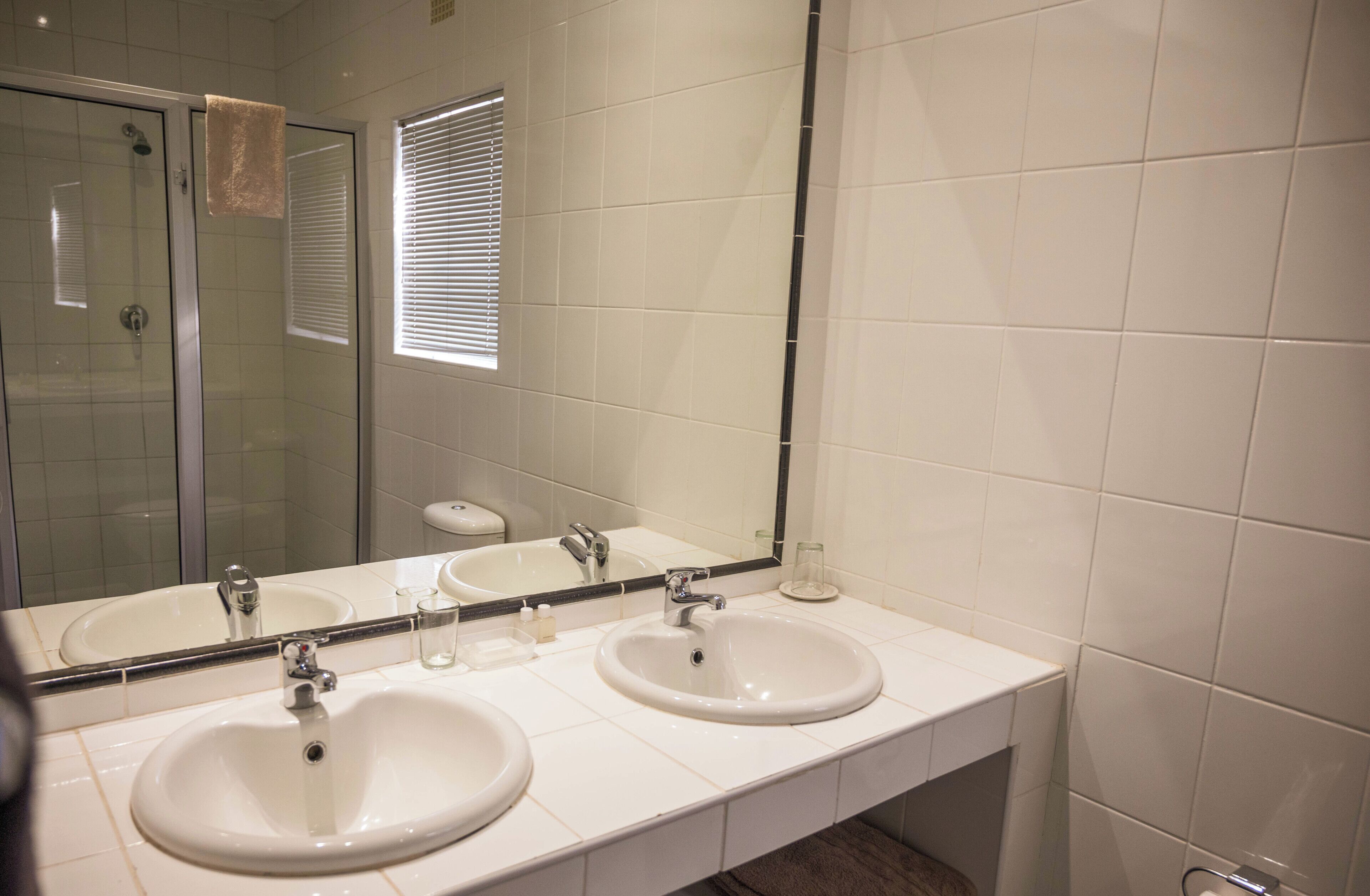 Une salle de bain avec deux lavabos, une douche à parois de verre et un grand miroir.