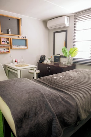 A bedroom with a bed, a desk, a vanity, and a large mirror.