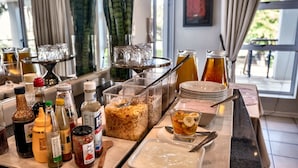 Um buffet de café da manhã com diversos alimentos, acompanhamentos e bebidas.