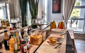Een ontbijtbuffet met diverse gerechten, sauzen en dranken.