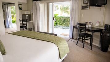 A hotel room with a bed, a desk, a chair, a television, and a view of the outdoors.