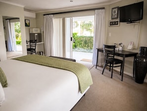 Una habitación de hotel con una cama, un escritorio, una silla, un televisor y vistas al exterior.