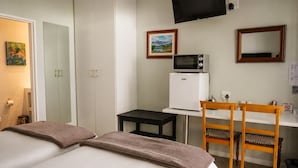 Ein Hotelzimmer mit einem Bett, einem Schreibtisch mit Mikrowelle, einem Sessel und einem Fernseher an der Wand.