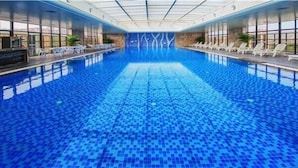 An indoor swimming pool with clear blue water, surrounded by lounge chairs and a glass ceiling. - Days Hotel & Suites Sichuan Jiangyou (Mianyang)