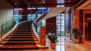A grand staircase in a hotel lobby with a glass railing, leading to a high ceiling and large windows. - Days Hotel & Suites Sichuan Jiangyou (Mianyang)