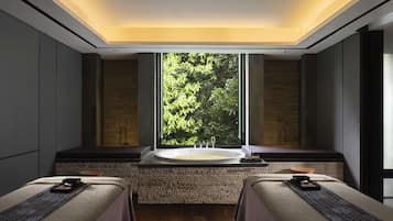 Relax in a serene space with a large bathtub and lush views, two beds, and a minimalist design.