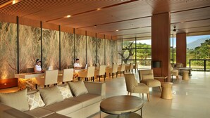 Un hall d’hôtel moderne doté d’un long comptoir d’accueil, de sièges confortables et de grandes fenêtres offrant une vue sur l’extérieur.