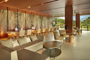 Eine moderne Hotelhalle mit einer langen Rezeption, bequemen Sitzgelegenheiten und großen Fenstern mit Blick ins Freie.