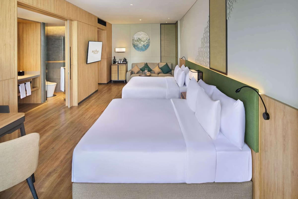 Ein Hotelzimmer mit einem großen Bett, einem Holzschrank, einem kleinen Tisch und einem Badezimmer mit Duschkabine.