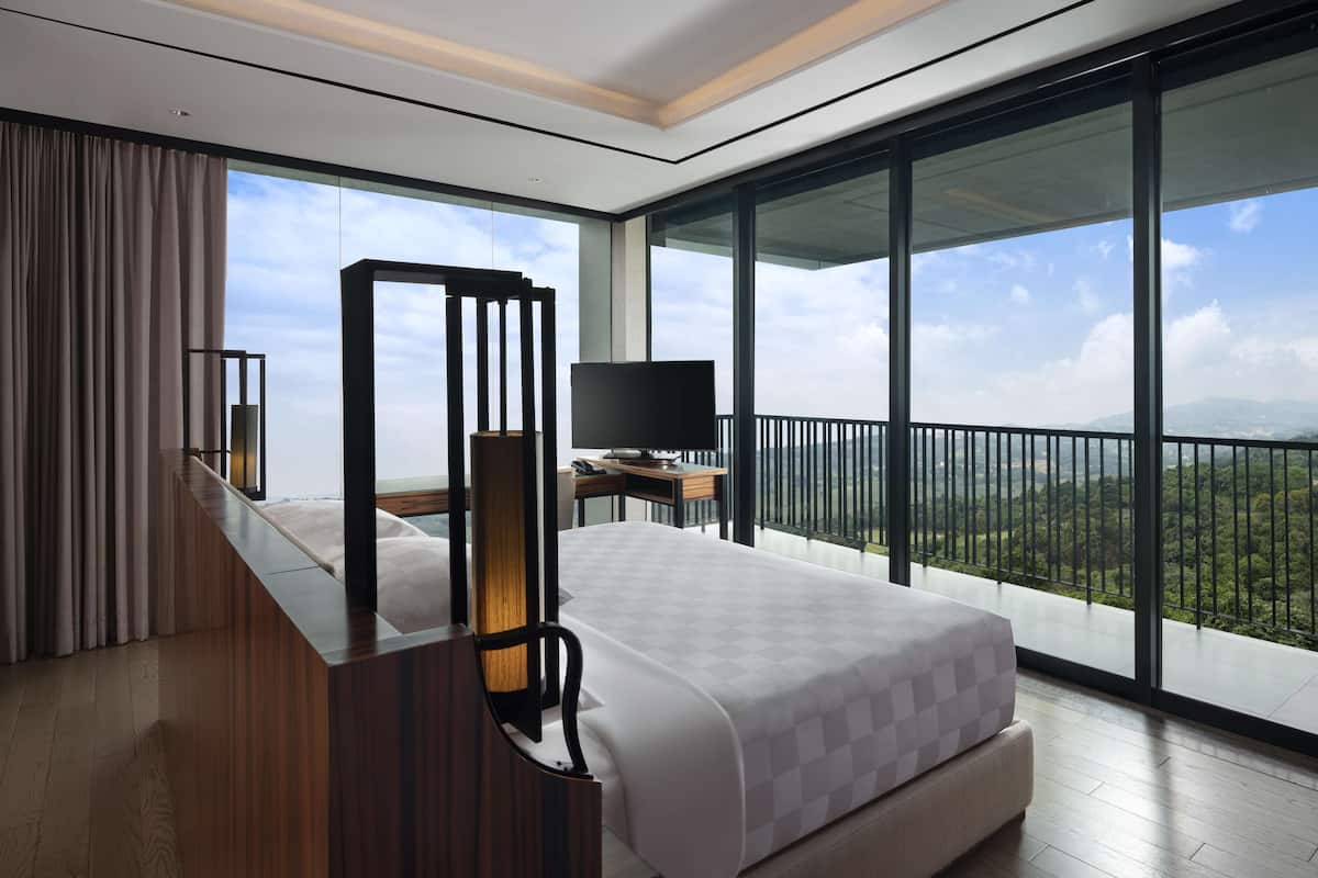 Ein modernes Hotelzimmer mit einem großen Bett, einem Schreibtisch mit Flachbildfernseher und einem Balkon mit schöner Aussicht.