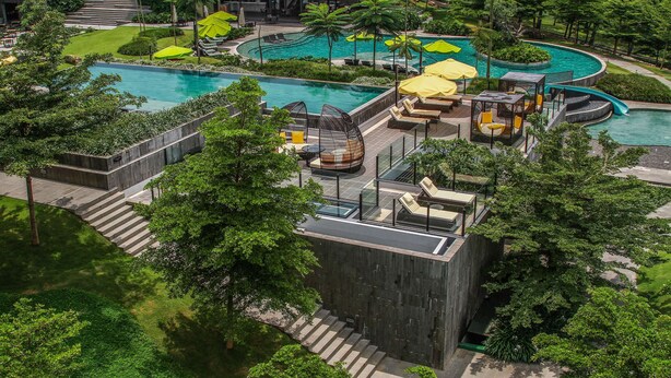 Ein Resort mit mehreren Swimmingpools, Außenbereichen zum Sitzen und üppiger Vegetation.