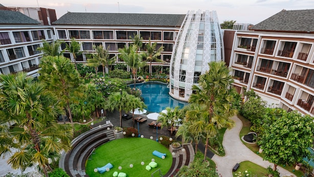 A hotel with a central pool, multiple balconies, and lush greenery. - Golden Tulip Jineng Resort Bali (Kuta)